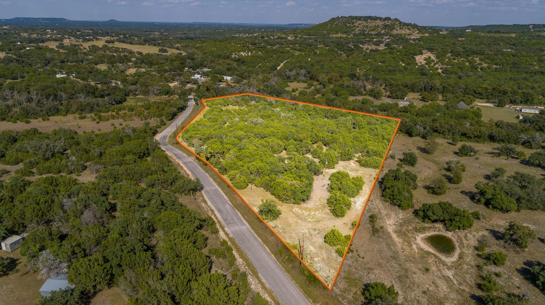 Aerial property-boundary overlay — wooded parcel along a hillside ranch, drawn over an orthographic drone aerial by Aerialcam Media